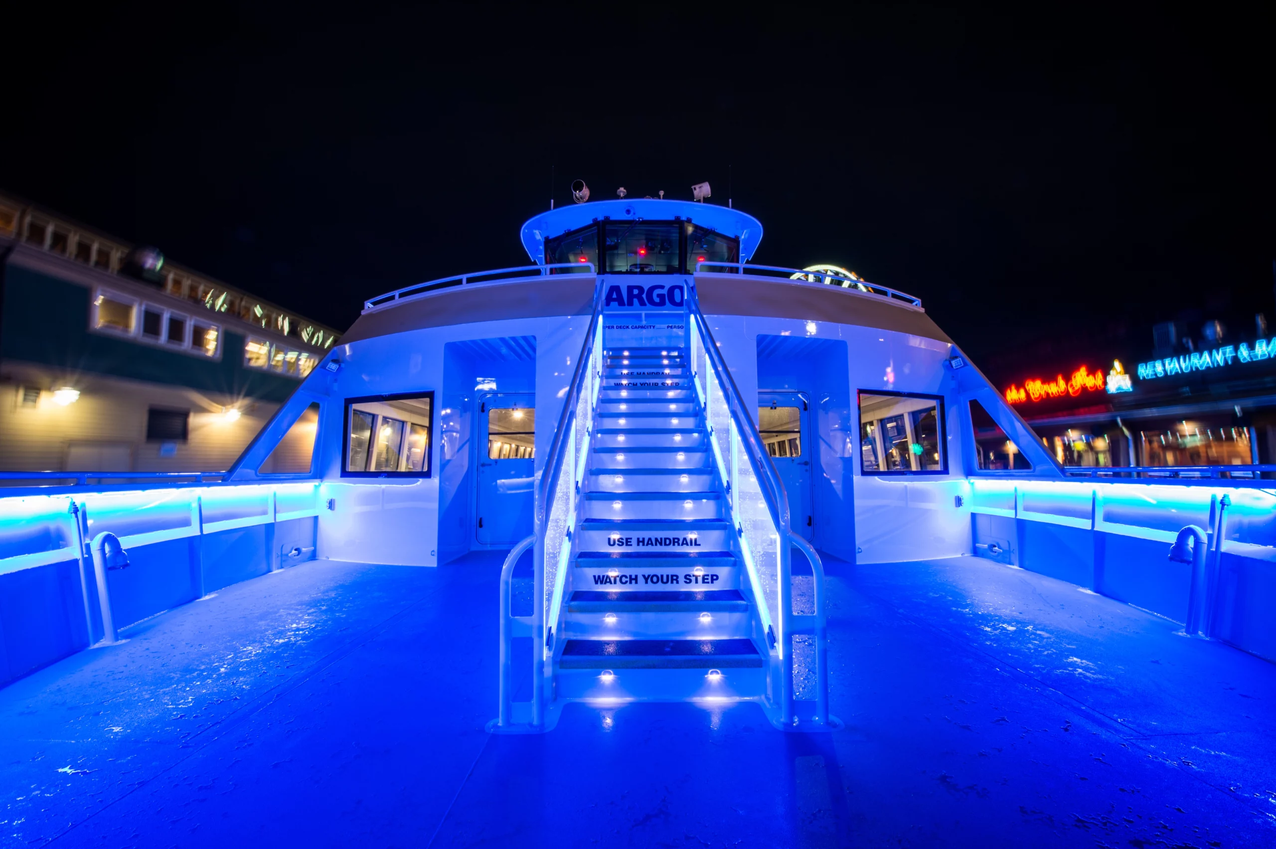 Night time photo of the Argosy Cruises private charter showing the deck bathed in blue light