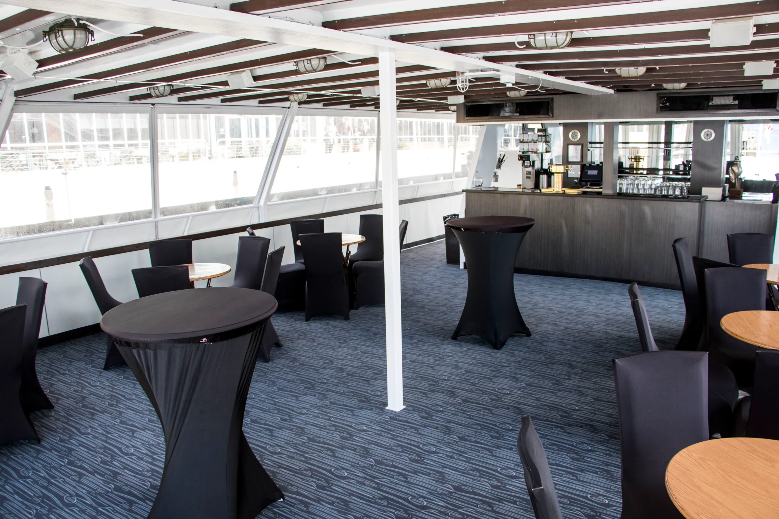 Extended view of the Argosy Cruises private charter bar and dining area, with tables and chairs.
